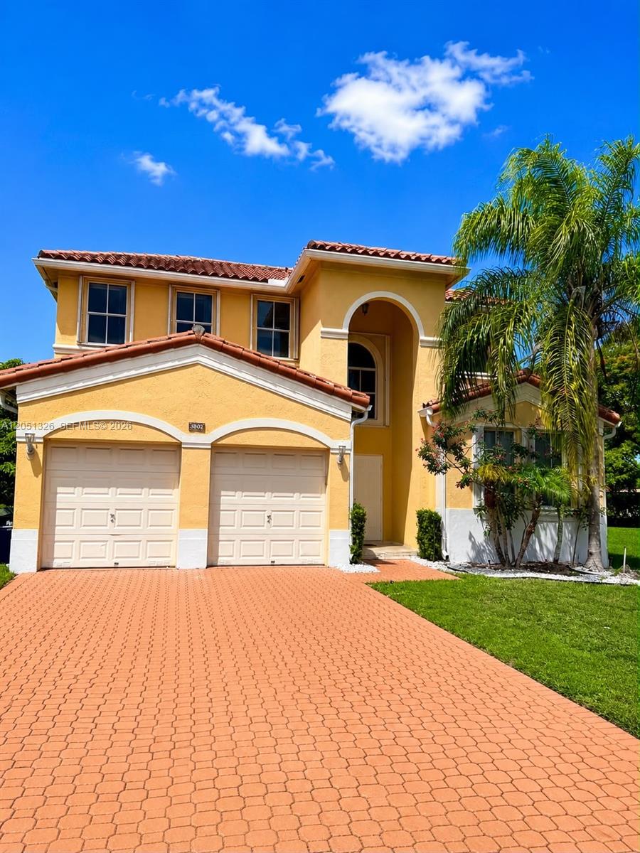 A two-story yellow stucco house features a two-car garage and a paved driveway — 3802 SW 165th Ter # 0, Miramar FL 33027, MIRAMAR, FL