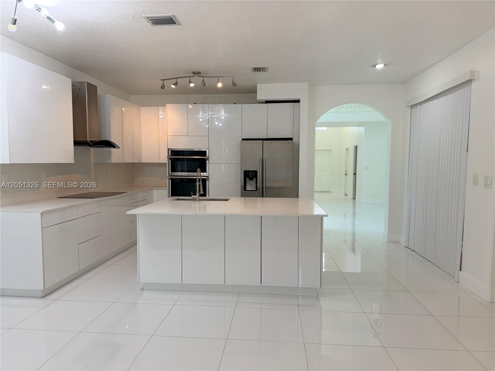 A modern white kitchen features glossy cabinets, stainless steel appliances, and a central island — 3802 SW 165th Ter # 0, Miramar FL 33027, MIRAMAR, FL