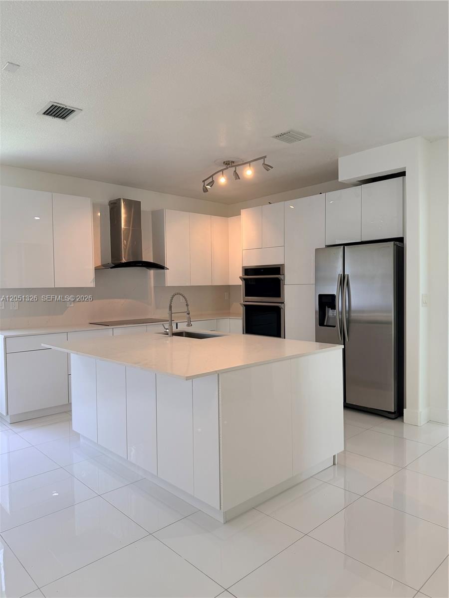 A modern kitchen features white glossy cabinets, a central island, and stainless steel appliances — 3802 SW 165th Ter # 0, Miramar FL 33027, MIRAMAR, FL
