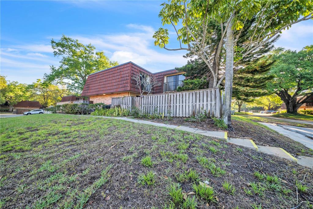 A two-story building with a mansard roof stands behind a wooden fence and grassy lawn — 2605 10TH COURT, PALM HARBOR, FL