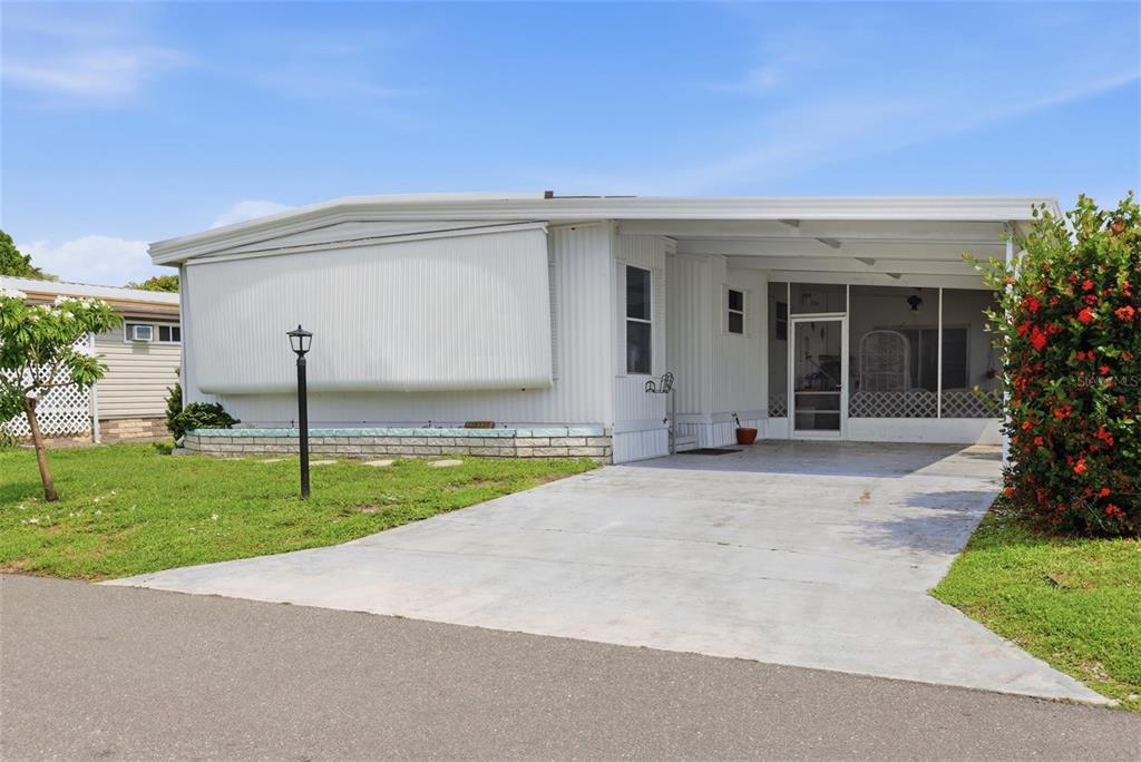 A white mobile home with a concrete driveway, a carport, and a screened-in porch — 6710 36TH AVENUE E UNIT 197, PALMETTO, FL