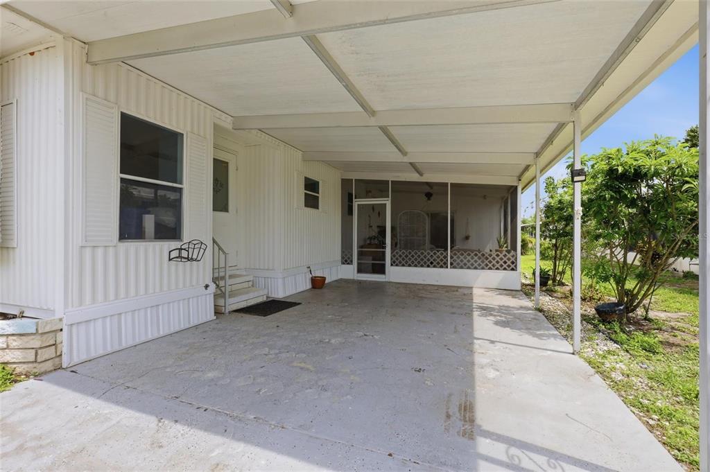 A concrete carport with a covered roof leads to a screened-in porch and home entrance — 6710 36TH AVENUE E UNIT 197, PALMETTO, FL