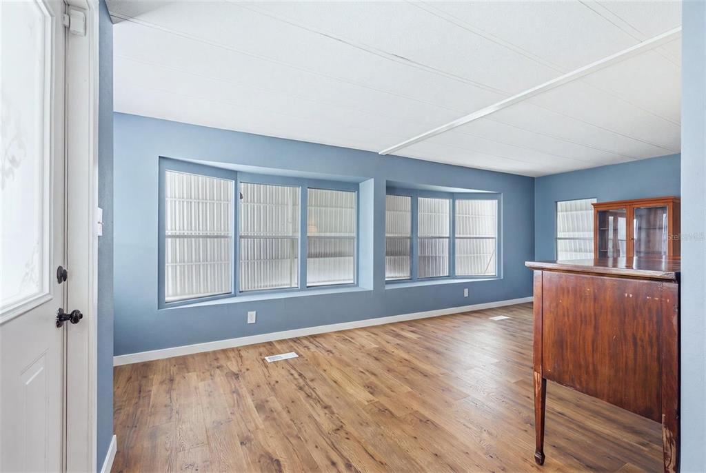 A room with blue walls, wood-look flooring, and two large bay windows — 6710 36TH AVENUE E UNIT 197, PALMETTO, FL