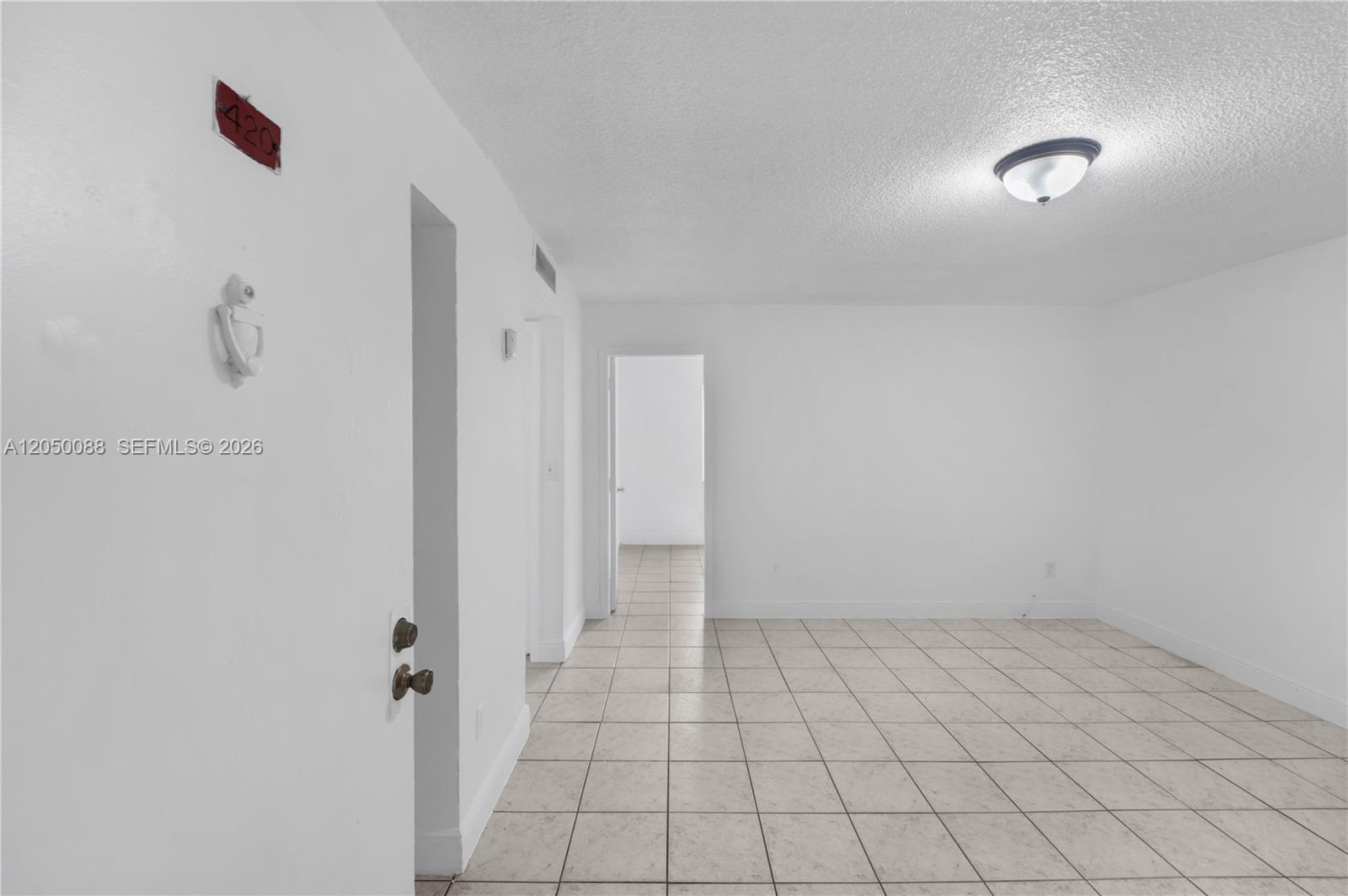 An empty room features white walls, light-colored tile flooring, and a ceiling-mounted light fixture — 1305 W 53rd St # 420, Hialeah FL 33012, HIALEAH, FL