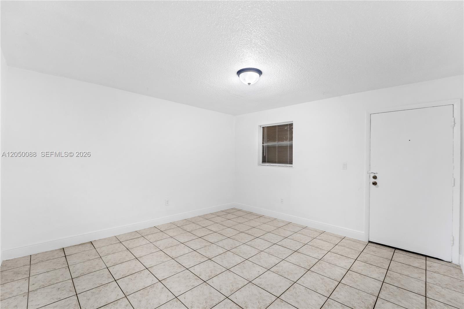 An empty room features white walls, a single window with blinds, and light-colored tile flooring — 1305 W 53rd St # 420, Hialeah FL 33012, HIALEAH, FL