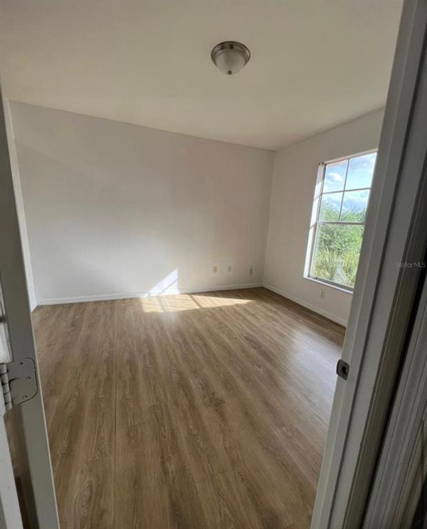 An empty bedroom features light wood-look flooring, white walls, and a single window — 5548 METROWEST BOULEVARD UNIT 306, ORLANDO, FL