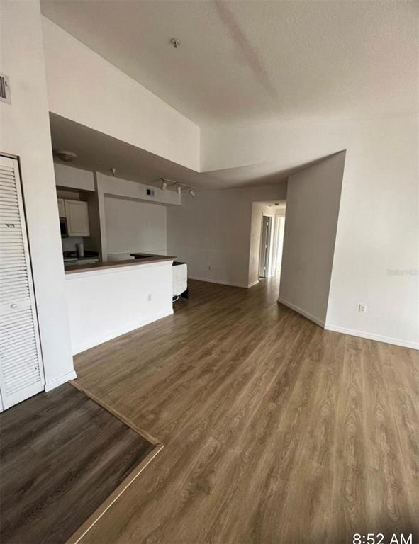 An interior view shows a living area with wood-look flooring leading to a kitchen counter — 5548 METROWEST BOULEVARD UNIT 306, ORLANDO, FL
