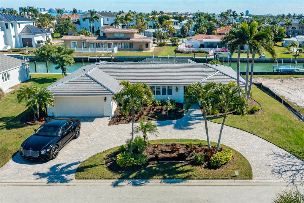 An aerial view shows a single-story house with a gray roof, circular driveway, and canal — 548 GUNWALE LANE, LONGBOAT KEY, FL