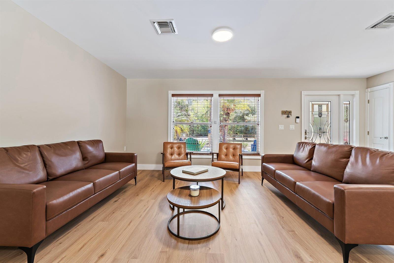 A living room features two brown leather sofas, two matching armchairs, and a tiered coffee table — 11217 169th Court N, Jupiter FL 33478, JUPITER, FL