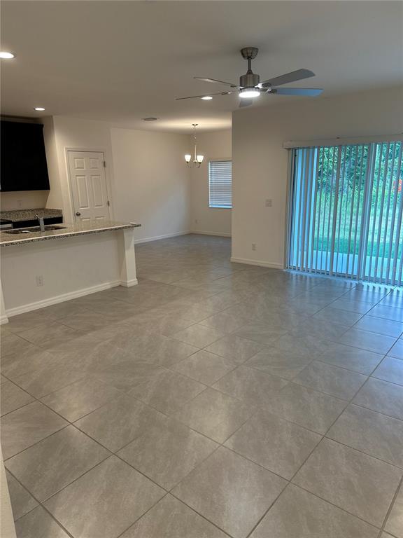 An open-concept living and dining area features light tile flooring and a sliding glass door — 189 GLASS ONION DRIVE, HOWEY IN THE HILLS, FL