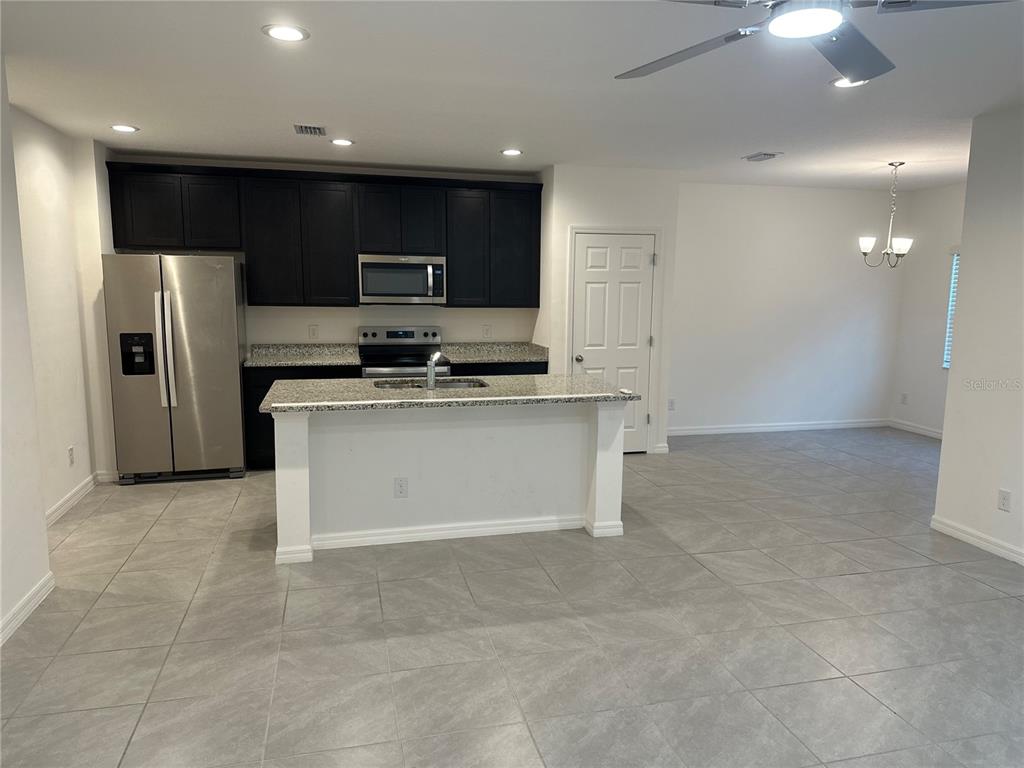 A kitchen features dark cabinets, stainless steel appliances, granite countertops, and a central island — 189 GLASS ONION DRIVE, HOWEY IN THE HILLS, FL