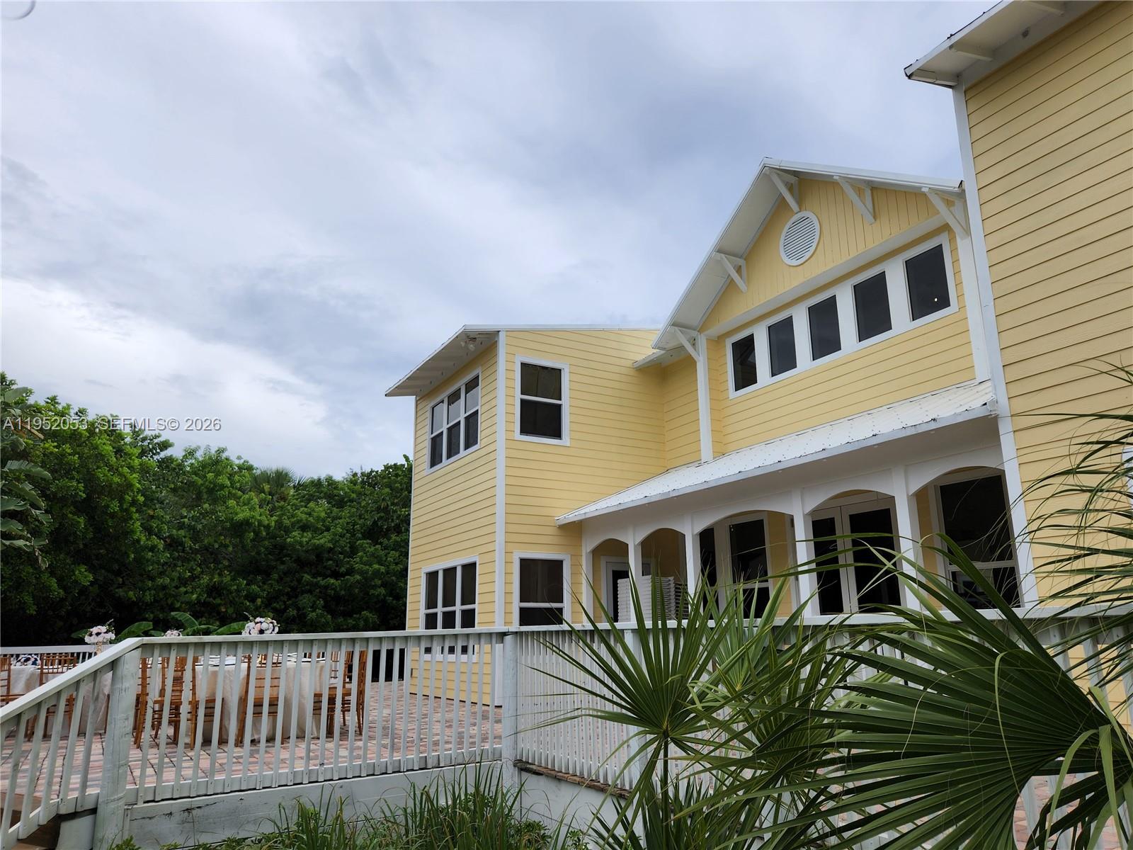 A yellow two-story house with a white porch and deck stands against a cloudy sky — 3601 N Highway A1a, Fort Pierce FL 34949, FORT PIERCE, FL