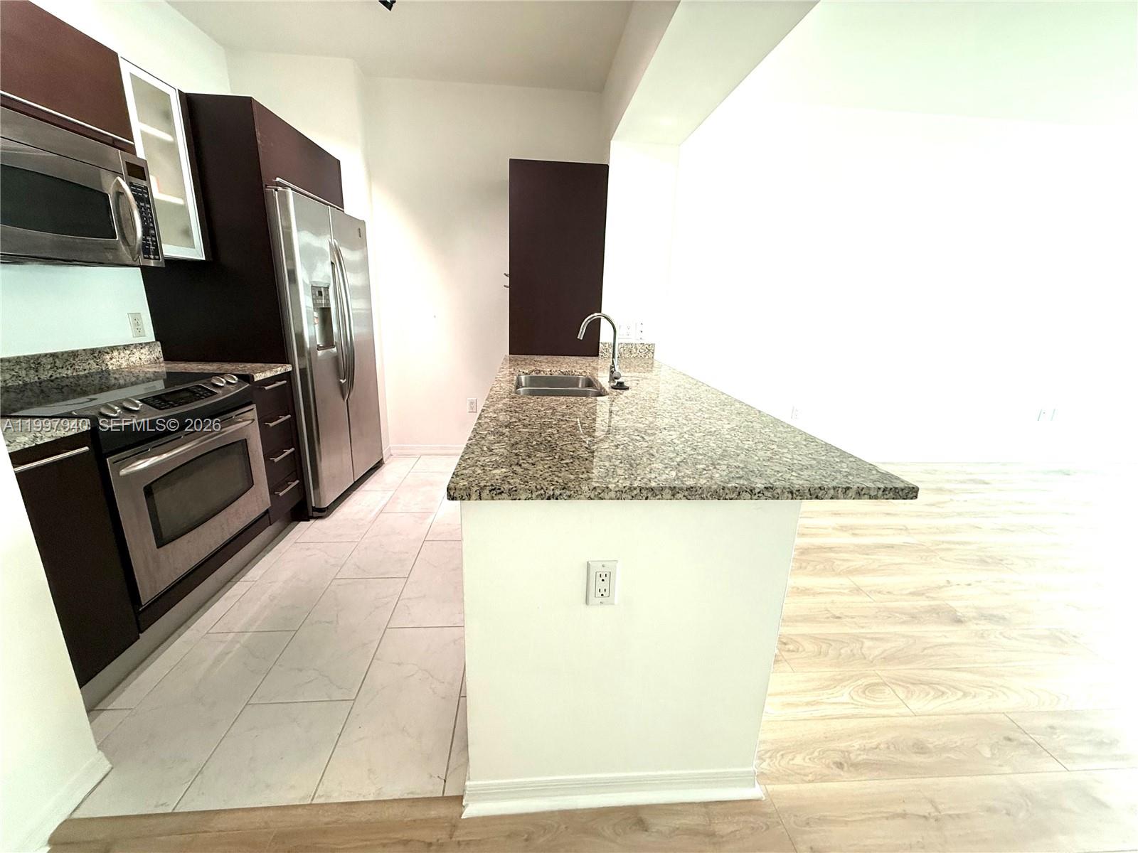 A kitchen features dark cabinets, stainless steel appliances, granite countertops, and a breakfast bar — 951 Brickell Ave # 1103, Miami FL 33131, MIAMI, FL