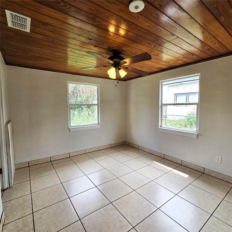 A room with light-colored tile flooring, plain walls, and a wood-paneled ceiling with a fan — 2710 AVENUE J NW, WINTER HAVEN, FL