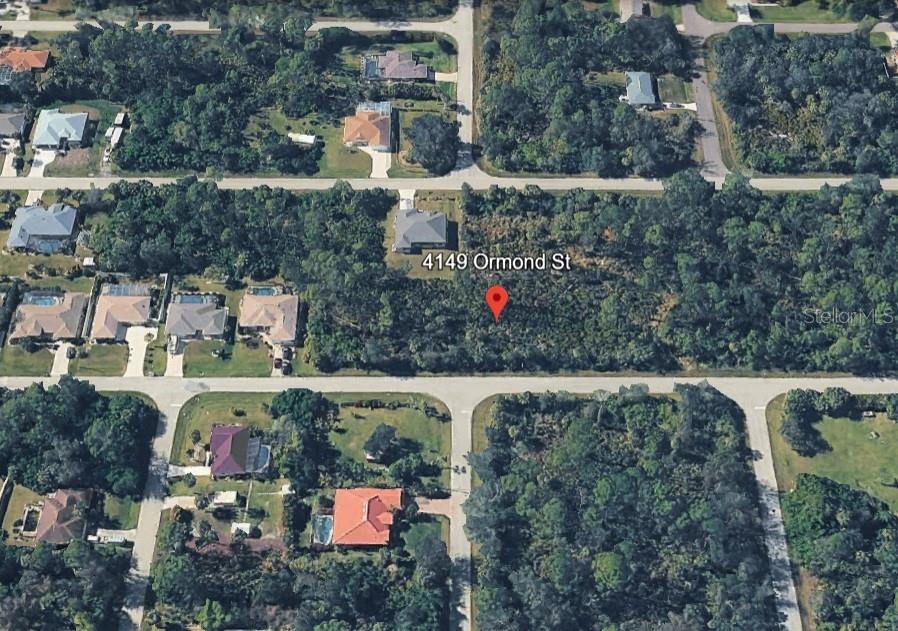 An aerial view shows a vacant, wooded residential lot surrounded by houses and paved streets — 4149 ORMOND STREET, PORT CHARLOTTE, FL