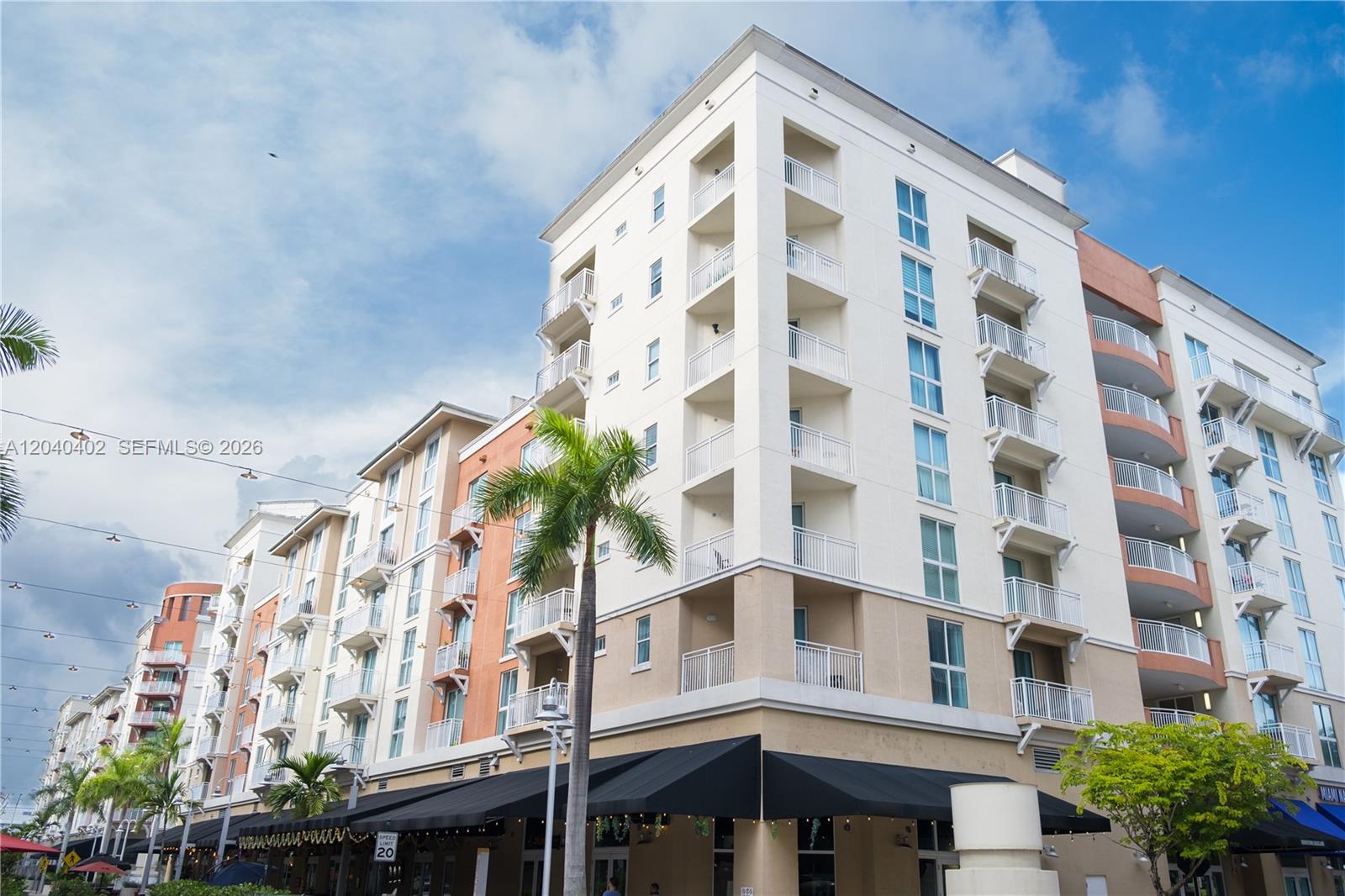 A multi-story apartment building with balconies and ground-floor retail space under black awnings — 7275 SW 90th St # C409, Miami FL 33156, MIAMI, FL