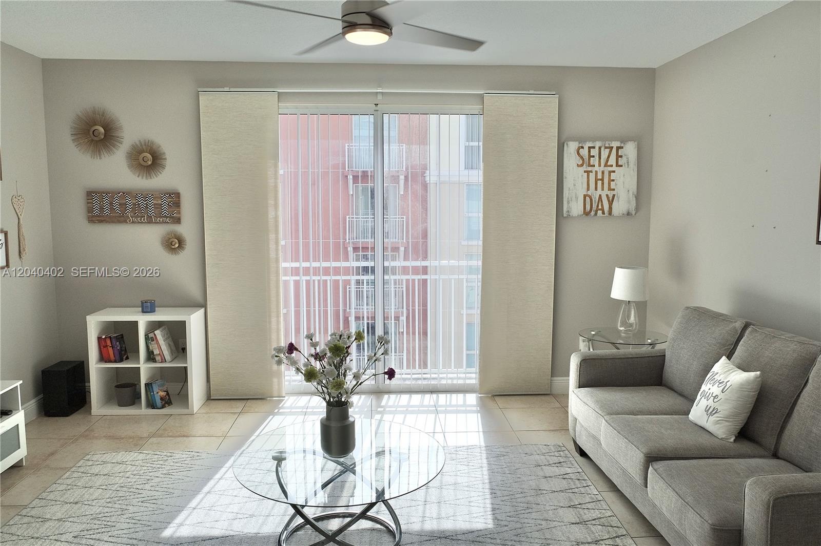 A living room features a gray sofa, glass coffee table, white shelving, and sliding glass doors — 7275 SW 90th St # C409, Miami FL 33156, MIAMI, FL