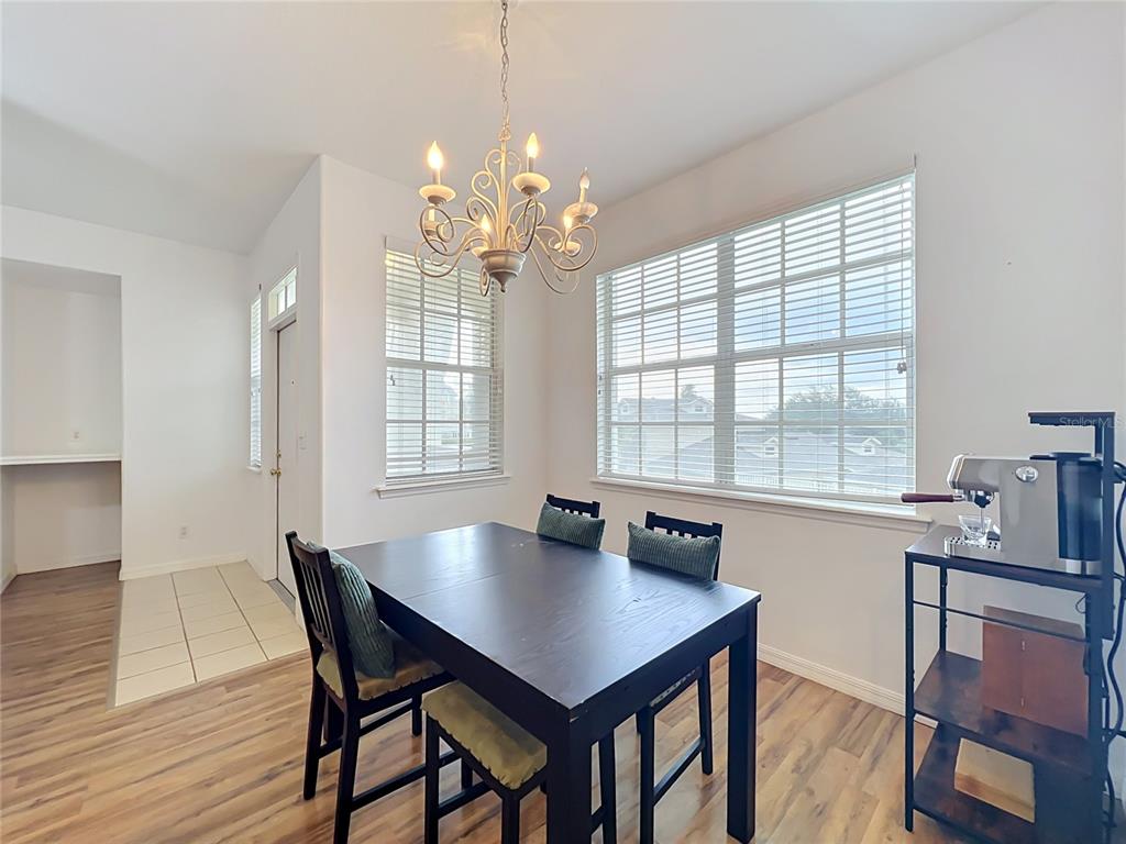 A dining area features a dark wood table, a chandelier, and windows with blinds — 17308 PROMENADE DRIVE, CLERMONT, FL