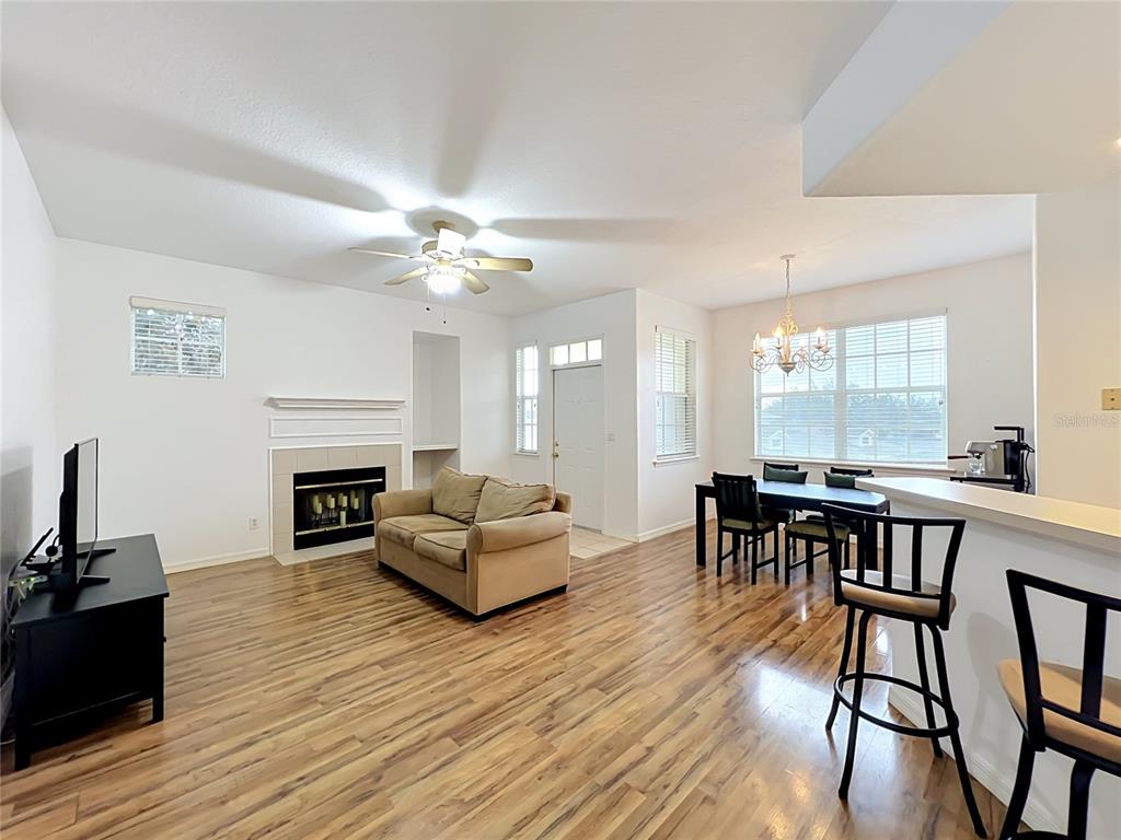 An open-concept living and dining area features a fireplace, hardwood floors, and a breakfast bar — 17308 PROMENADE DRIVE, CLERMONT, FL