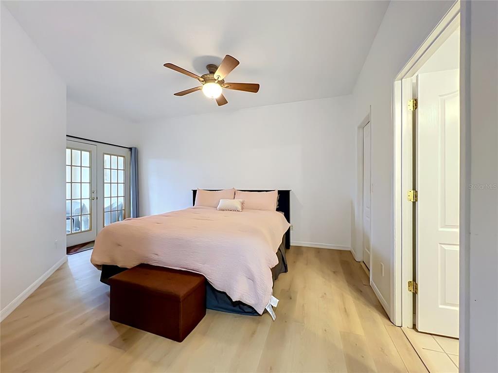 A bedroom features light wood flooring, a bed with pink bedding, and a ceiling fan — 17308 PROMENADE DRIVE, CLERMONT, FL