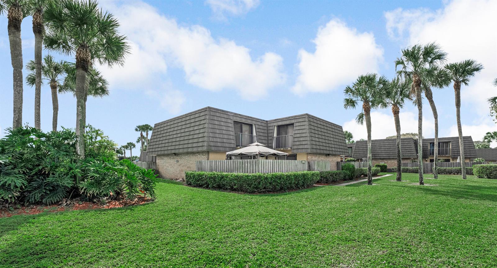 A two-story residential building with a mansard roof sits behind a manicured lawn and palms — 2439 24th Way # 2439, West Palm Beach FL 33407, WEST PALM BEACH, FL