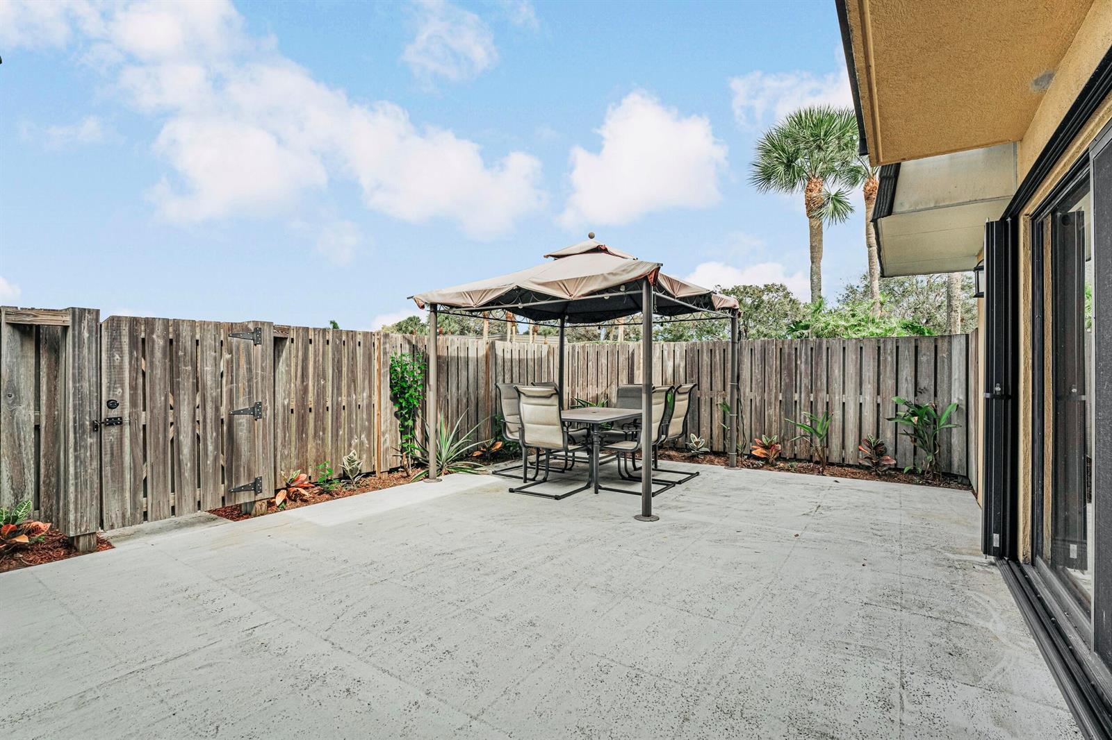 A concrete patio features a gazebo with a dining set enclosed by a wooden fence — 2439 24th Way # 2439, West Palm Beach FL 33407, WEST PALM BEACH, FL