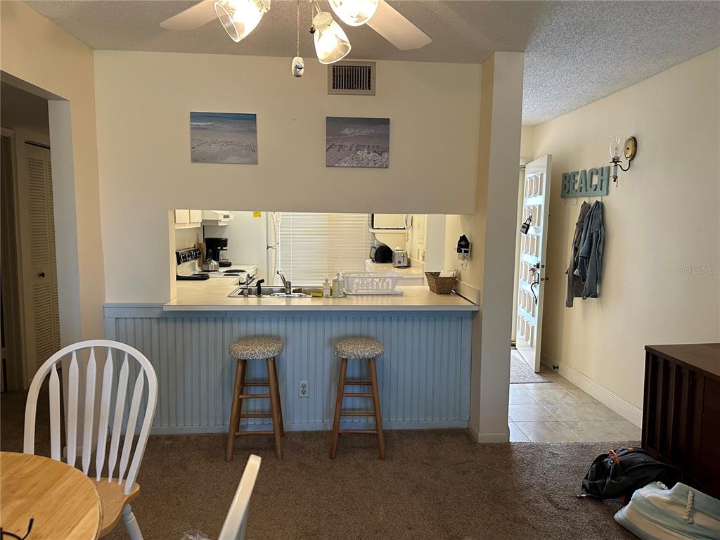 A kitchen pass-through window overlooks a breakfast bar with two stools and light blue wainscoting — 6219 PALMA DEL MAR BOULEVARD S UNIT 210, ST PETERSBURG, FL