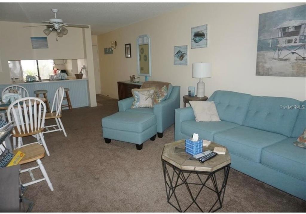 A living room features a blue sofa, matching armchair with ottoman, and a dining area — 6219 PALMA DEL MAR BOULEVARD S UNIT 210, ST PETERSBURG, FL