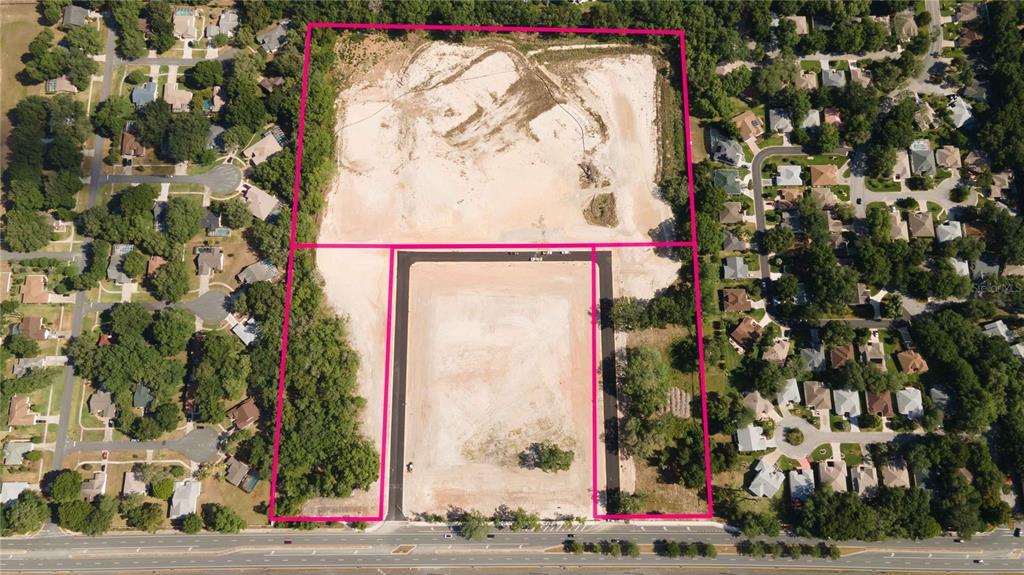 An aerial view shows a large, cleared plot of land outlined in pink near residential homes — 1135 HWY 466, LADY LAKE, FL