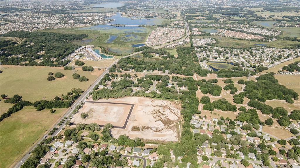 An aerial view shows a cleared construction site surrounded by residential neighborhoods and green space — 1135 HWY 466, LADY LAKE, FL