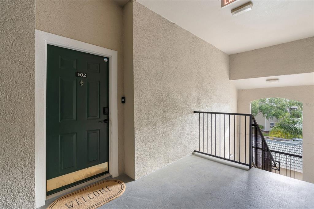 A green apartment door labeled 302 sits on a concrete landing with a metal railing — 5160 NORTHRIDGE ROAD UNIT 302, SARASOTA, FL