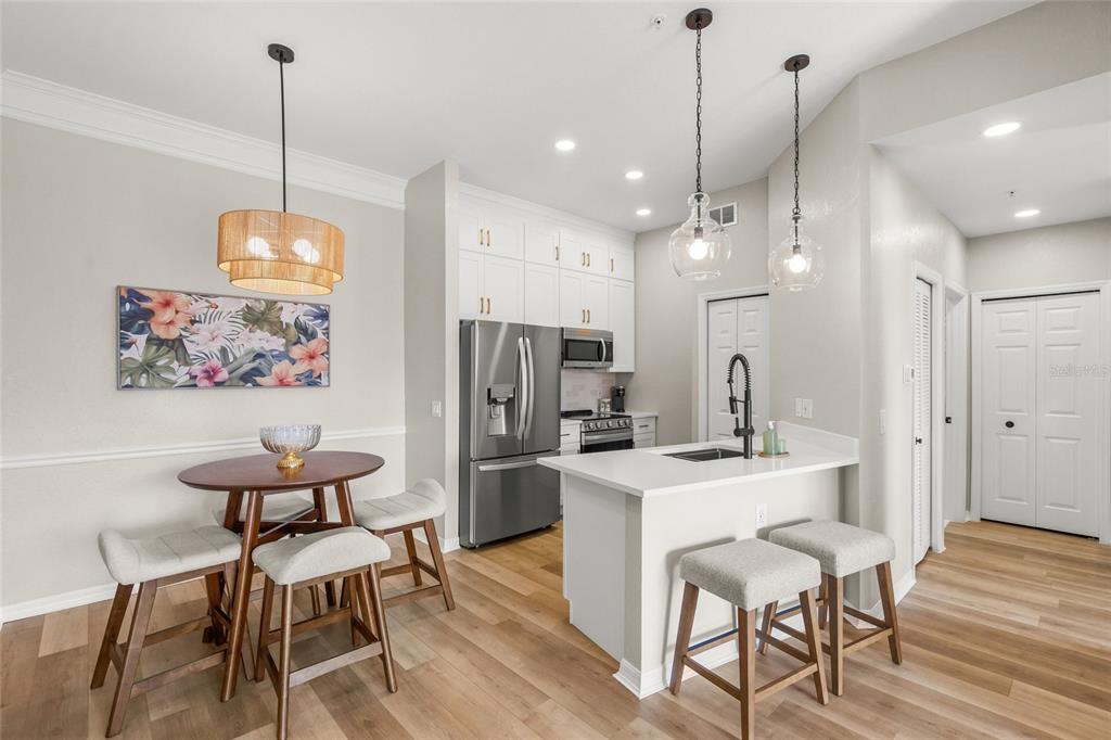 A kitchen and dining area with stainless steel appliances, white cabinetry, and light wood flooring — 5160 NORTHRIDGE ROAD UNIT 302, SARASOTA, FL