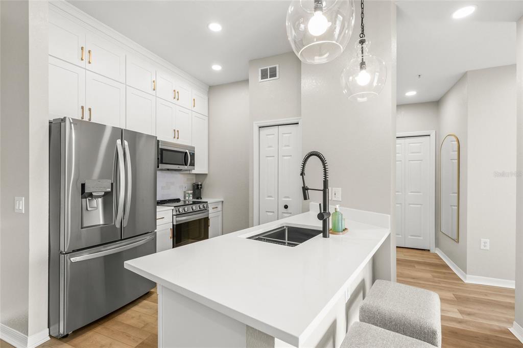 A modern kitchen features white cabinetry, stainless steel appliances, and a white quartz island — 5160 NORTHRIDGE ROAD UNIT 302, SARASOTA, FL