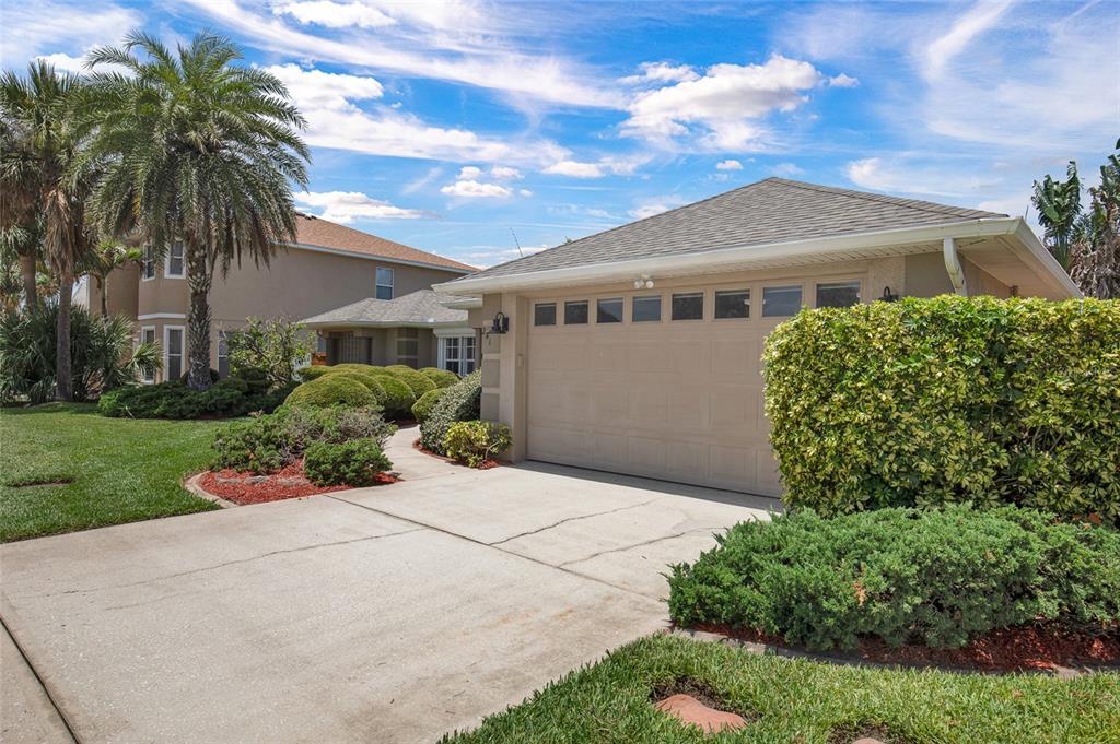 A beige house with a two-car garage, a concrete driveway, and manicured landscaping — 241 CORONA AVENUE, COCOA BEACH, FL
