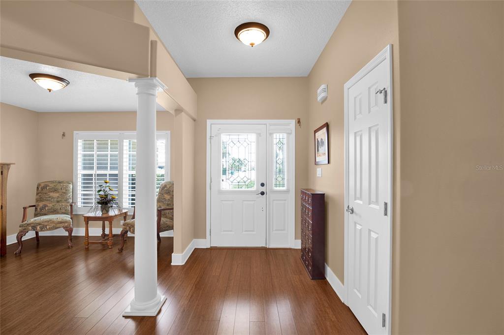 A foyer with hardwood floors, a white column, and a front door with glass inserts — 241 CORONA AVENUE, COCOA BEACH, FL
