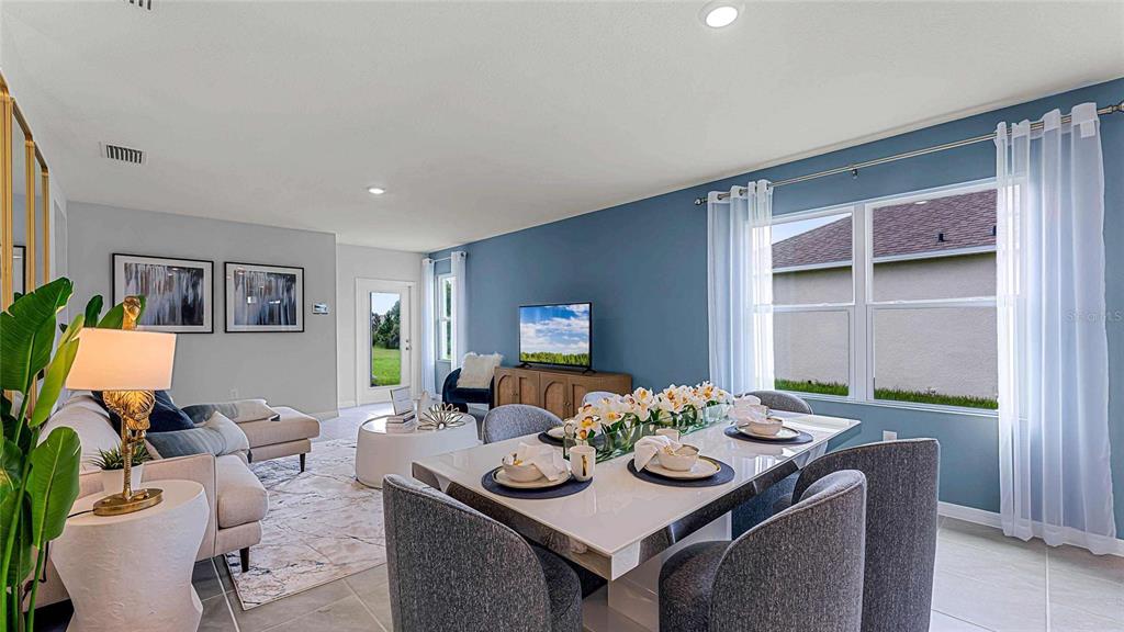 A dining area with a white table and grey chairs opens into a living room — 17951 ACORN DROP ROAD, LAND O LAKES, FL
