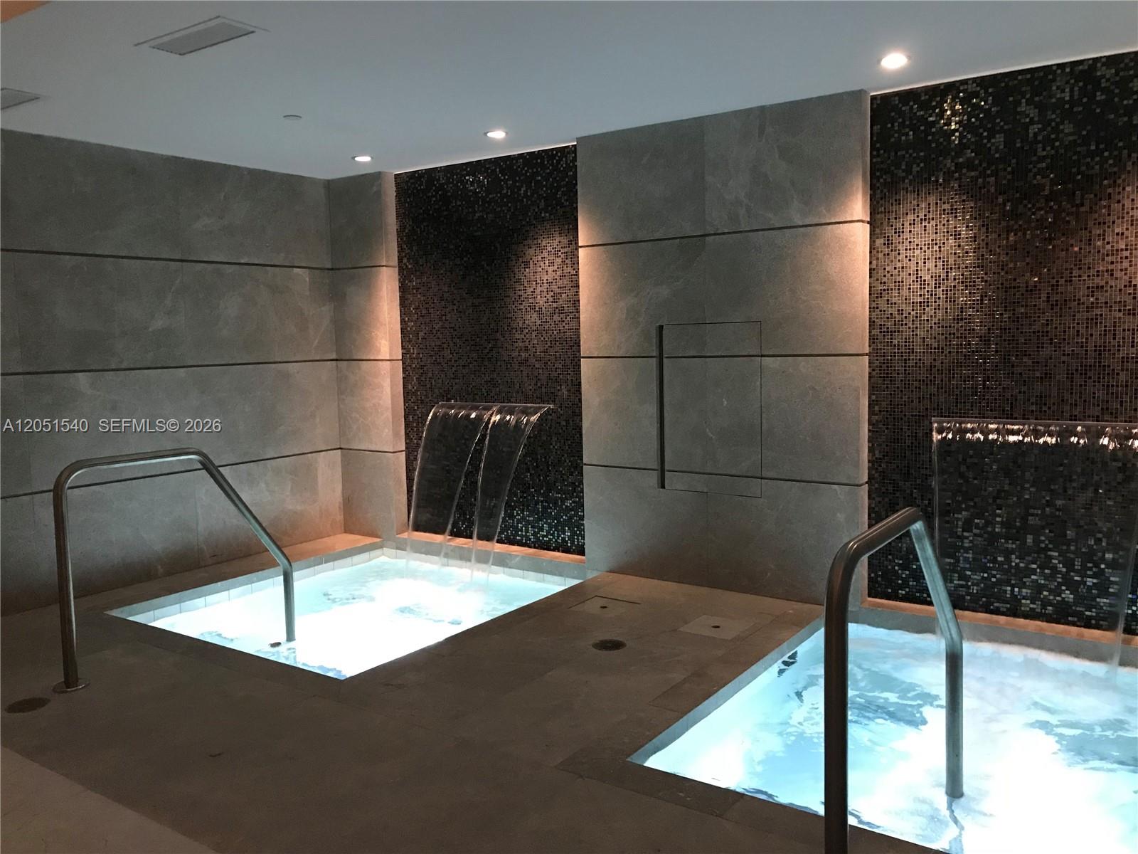Two indoor hot tubs with waterfall features are set against dark tiled walls — 1010 Brickell Ave # 3309, Miami FL 33131, MIAMI, FL