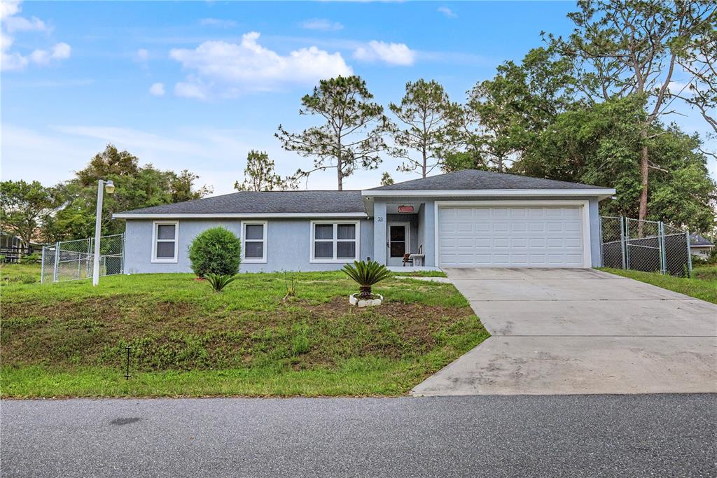 A single-story house with a gray exterior, white garage door, and a concrete driveway — 23 JUNIPER TRAIL CIRCLE, OCALA, FL