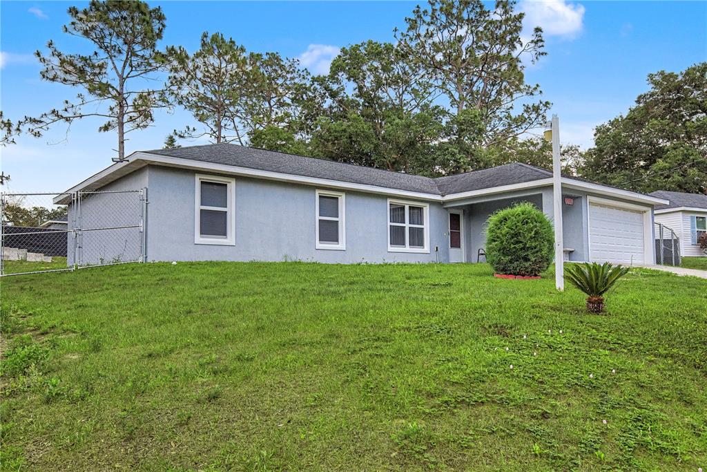 A single-story house with a gray stucco exterior, a shingled roof, and a front lawn — 23 JUNIPER TRAIL CIRCLE, OCALA, FL