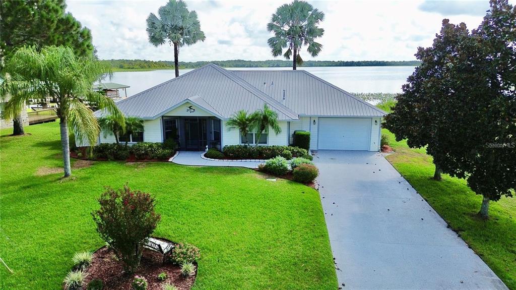 A waterfront property features a house, a boat dock with a covered slip, and vegetation — 2608 PINE NEEDLE DRIVE, SEBRING, FL