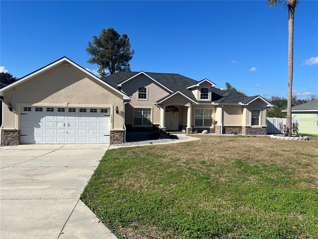 A single-story house with a beige stucco exterior, stone accents, and a two-car garage — 1035 SW 33RD PLACE, OCALA, FL