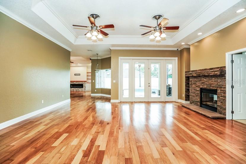 A spacious living room features hardwood floors, a stone fireplace, and two ceiling fans — 1035 SW 33RD PLACE, OCALA, FL