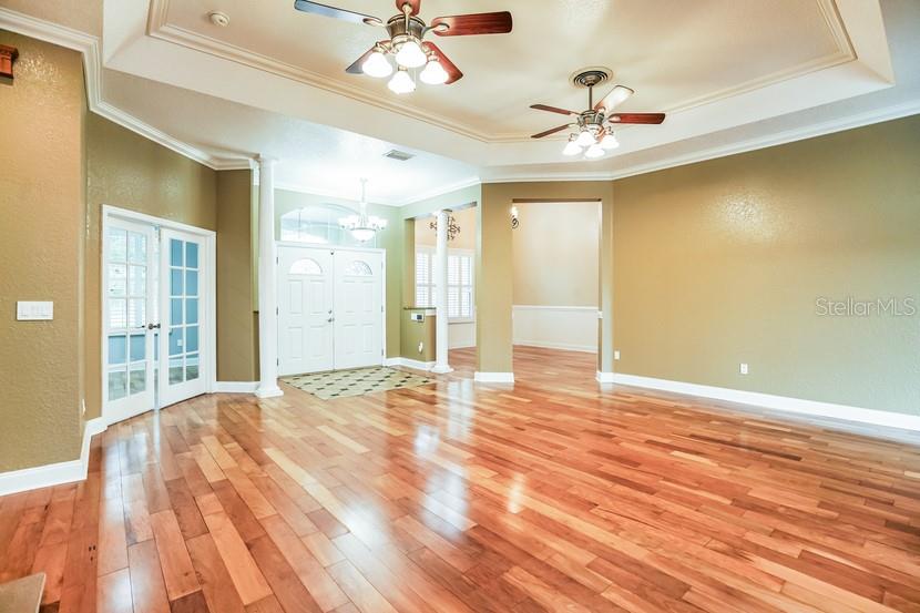 A spacious room features hardwood floors, two ceiling fans, and white double doors — 1035 SW 33RD PLACE, OCALA, FL