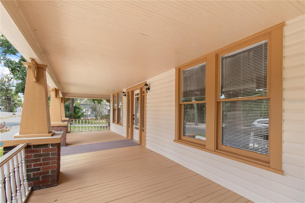 A covered front porch features a wooden floor, brick-based columns, and white siding — 907 N CLARK STREET, PLANT CITY, FL
