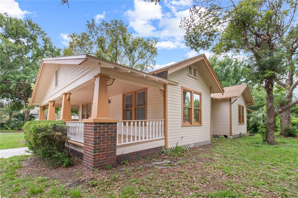 A tan bungalow with a brick-based front porch, white railings, and brown window trim — 907 N CLARK STREET, PLANT CITY, FL