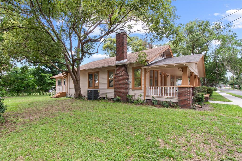 A side view of a single-story house with a brick chimney and a front porch — 907 N CLARK STREET, PLANT CITY, FL
