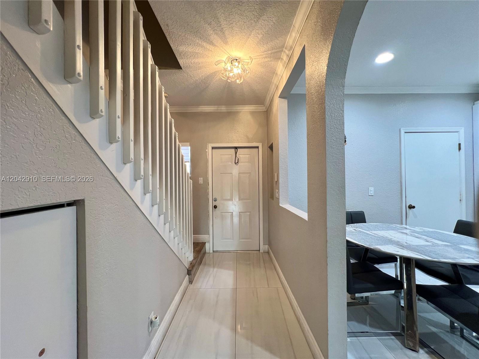A tiled entryway features a staircase with white railings and an arched opening to a dining area — 8917 NW 54th St, Sunrise FL 33351, SUNRISE, FL