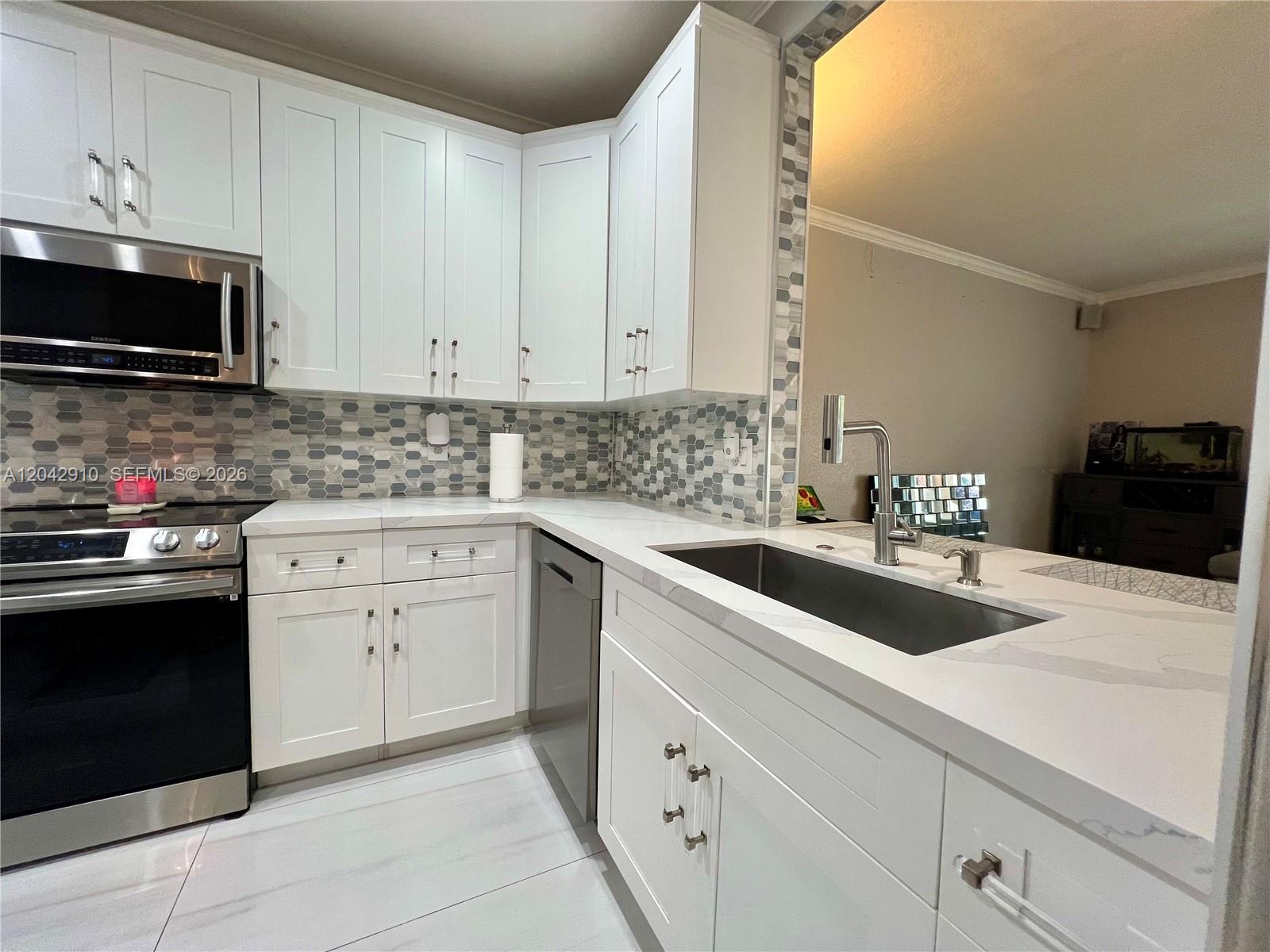 A modern kitchen features white shaker cabinets, quartz countertops, and a gray hexagonal tile backsplash — 8917 NW 54th St, Sunrise FL 33351, SUNRISE, FL