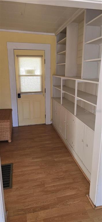 A room with wood-look flooring, a yellow door, and built-in white shelving and cabinets — 315 VIRGINIA STREET, FROSTPROOF, FL