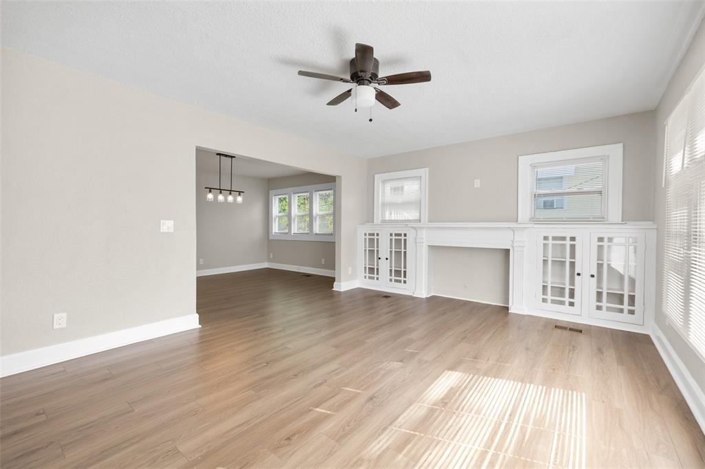 A living room with light wood flooring, a ceiling fan, and a white built-in fireplace — 781 31ST AVENUE N, ST PETERSBURG, FL